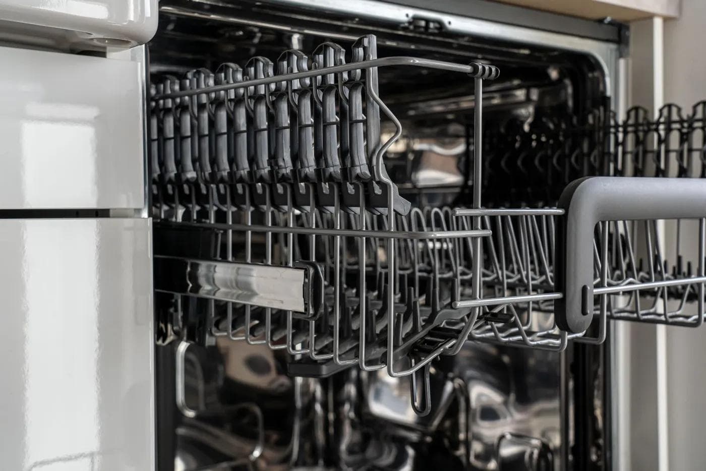 Open dishwasher with empty stainless steel racks