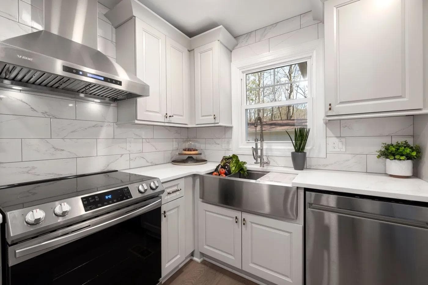 White kitchen with a stainless steel range, range hood, and dishwasher