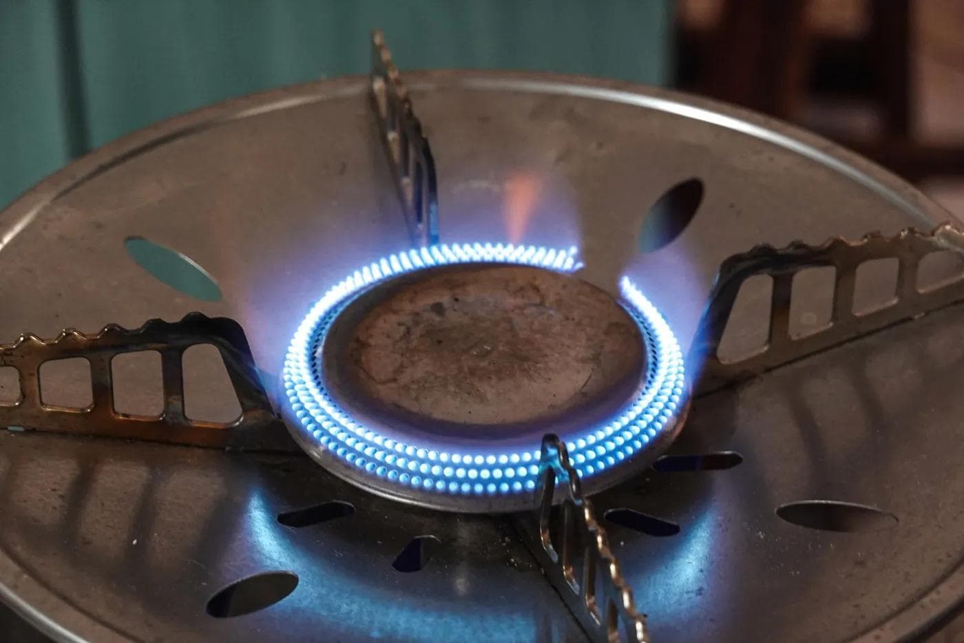 Close-up of a lit gas burner ring with small blue flames