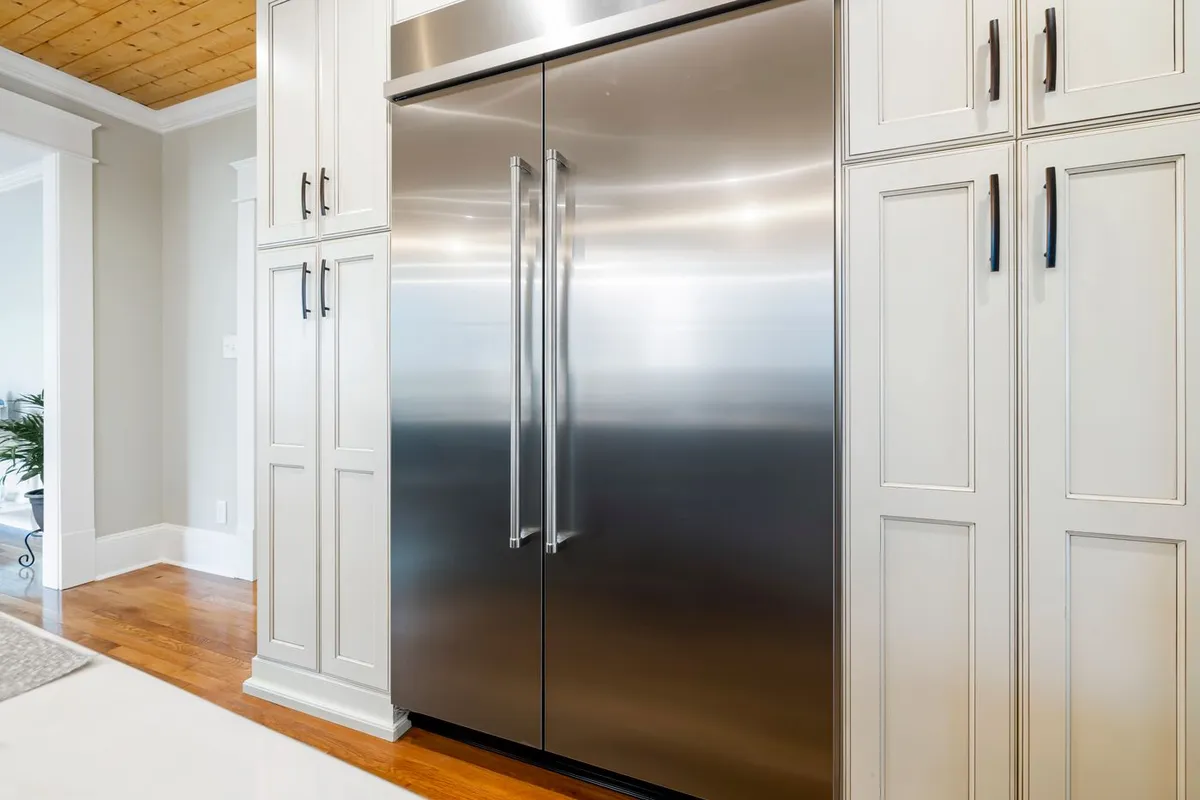 Built-in stainless steel refrigerator column between white cabinets
